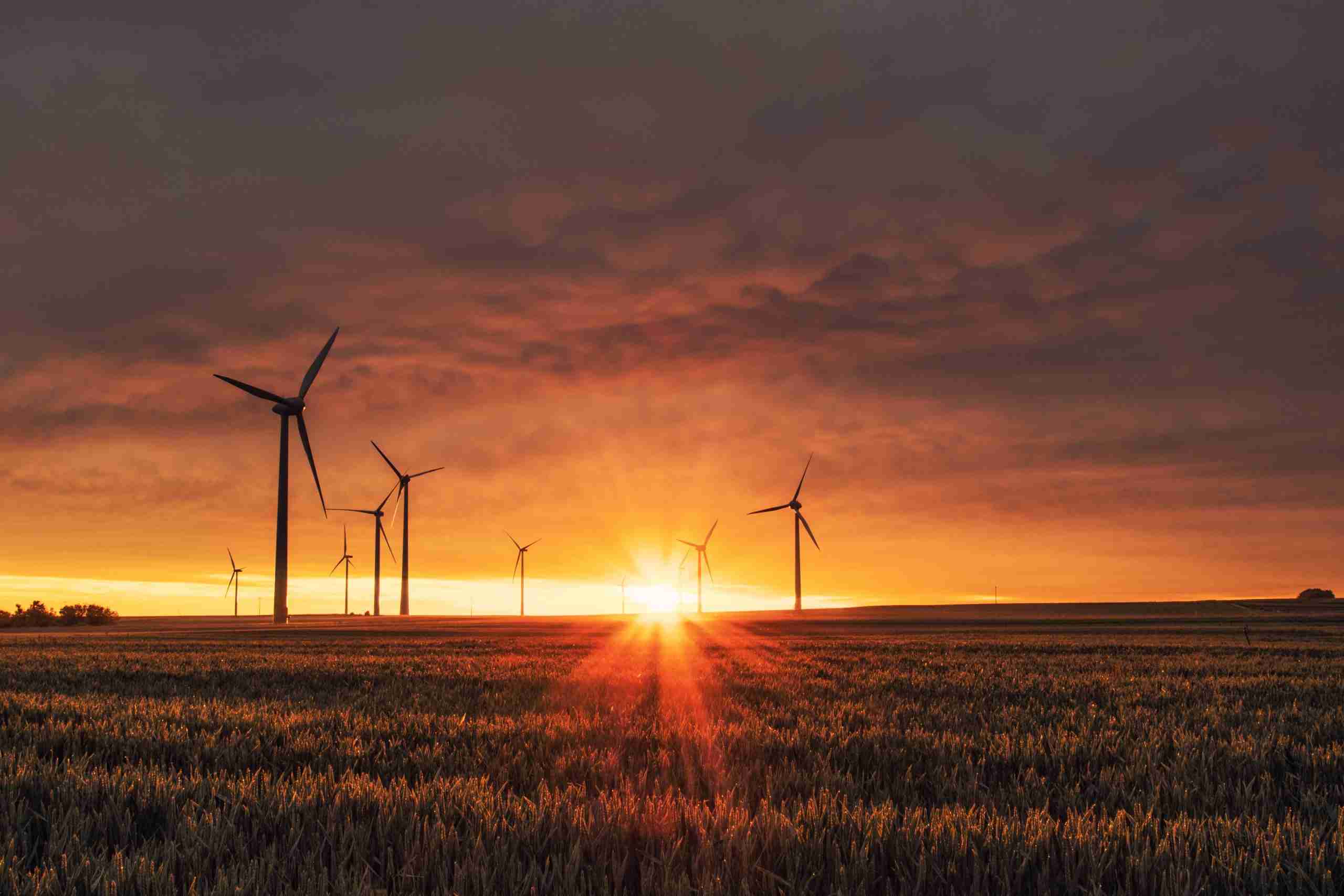 Wind turbines silhouetted against a vibrant sunset, showcasing renewable energy in harmony with nature's beauty.